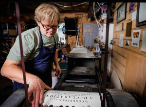 Utah artist Rob Buchert examines a freshly printed sheet of his recreation of the 1776 Declaration of Independence from the press. Every copy was printed one sheet at a time, by hand, on paper he made himself using 18th century methods