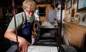 Utah artist Rob Buchert examines a freshly printed sheet of his recreation of the 1776 Declaration of Independence from the press. Every copy was printed one sheet at a time, by hand, on paper he made himself using 18th century methods